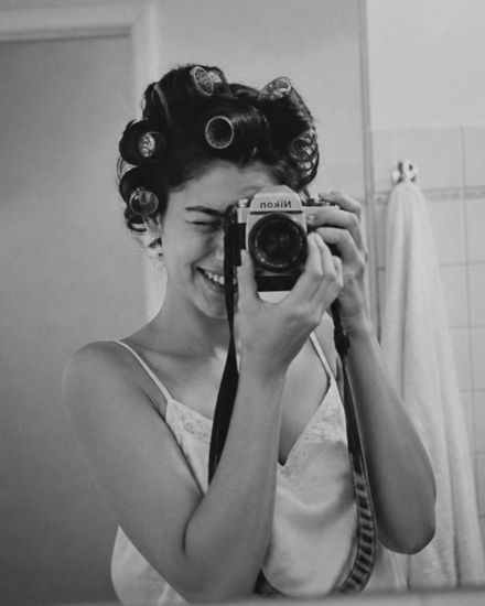 Girl in curlers photographing herself in the bathroom mirror, black and white.