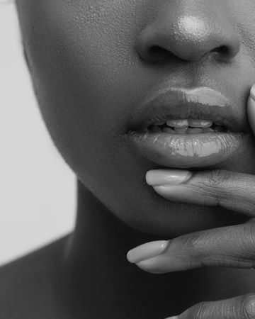 Close-up of glossy lips, muted tones.